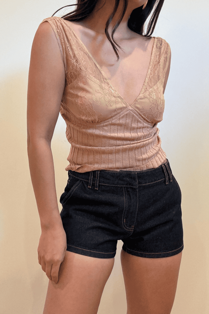 Woman in lace top and denim shorts.