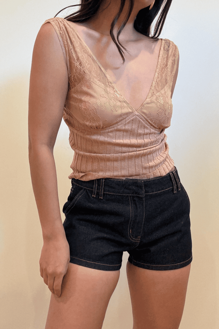 Woman in lace top and denim shorts.
