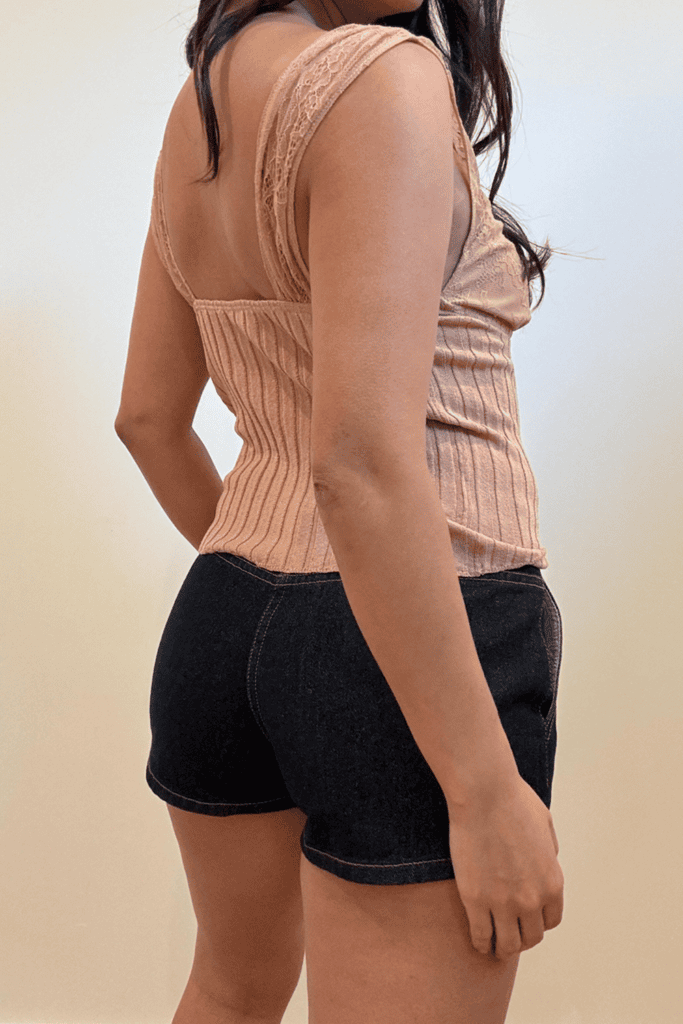 Woman in beige top and black shorts.