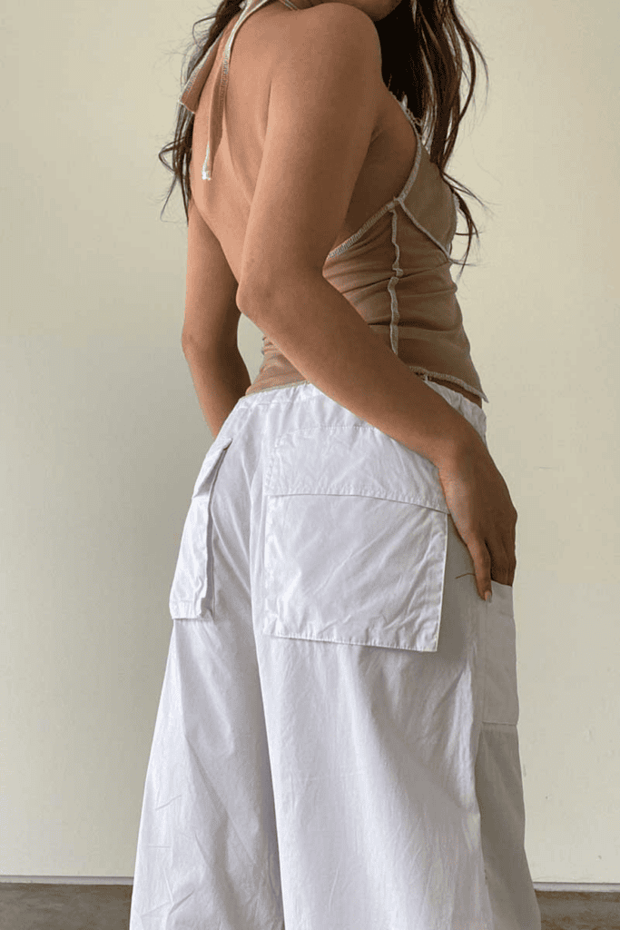 Woman in beige top and white pants.