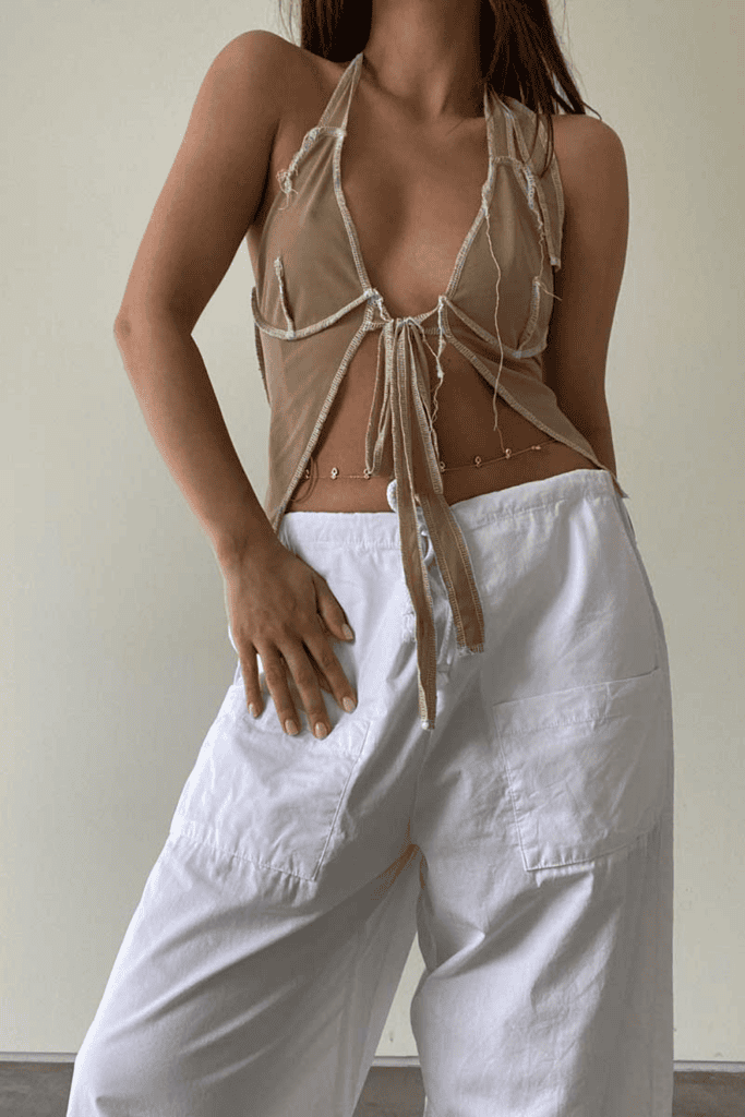 Woman in stylish top and white pants.