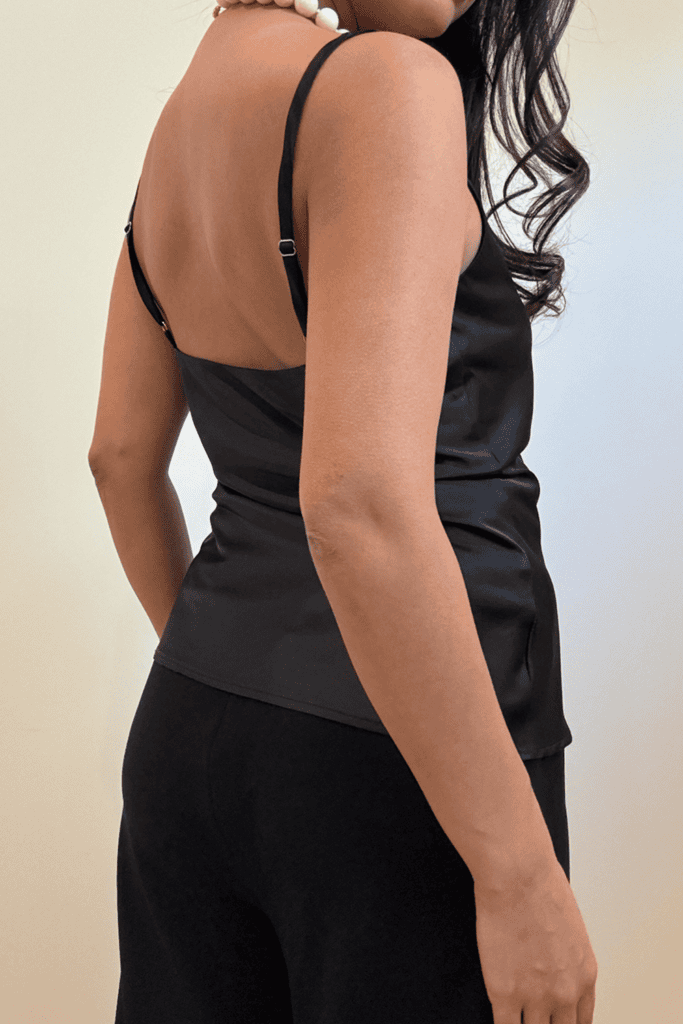 Woman wearing black satin top, side view.