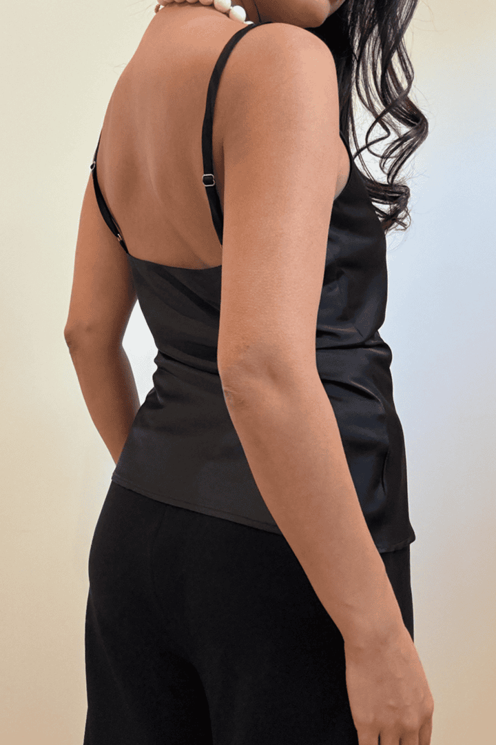 Woman wearing black satin top, side view.