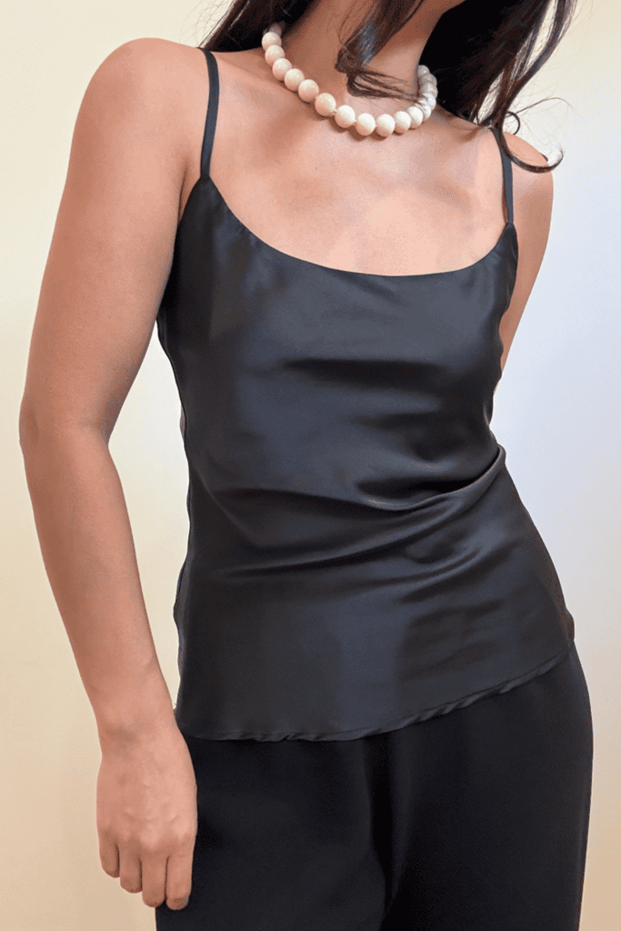 Woman in black satin top and pearls.